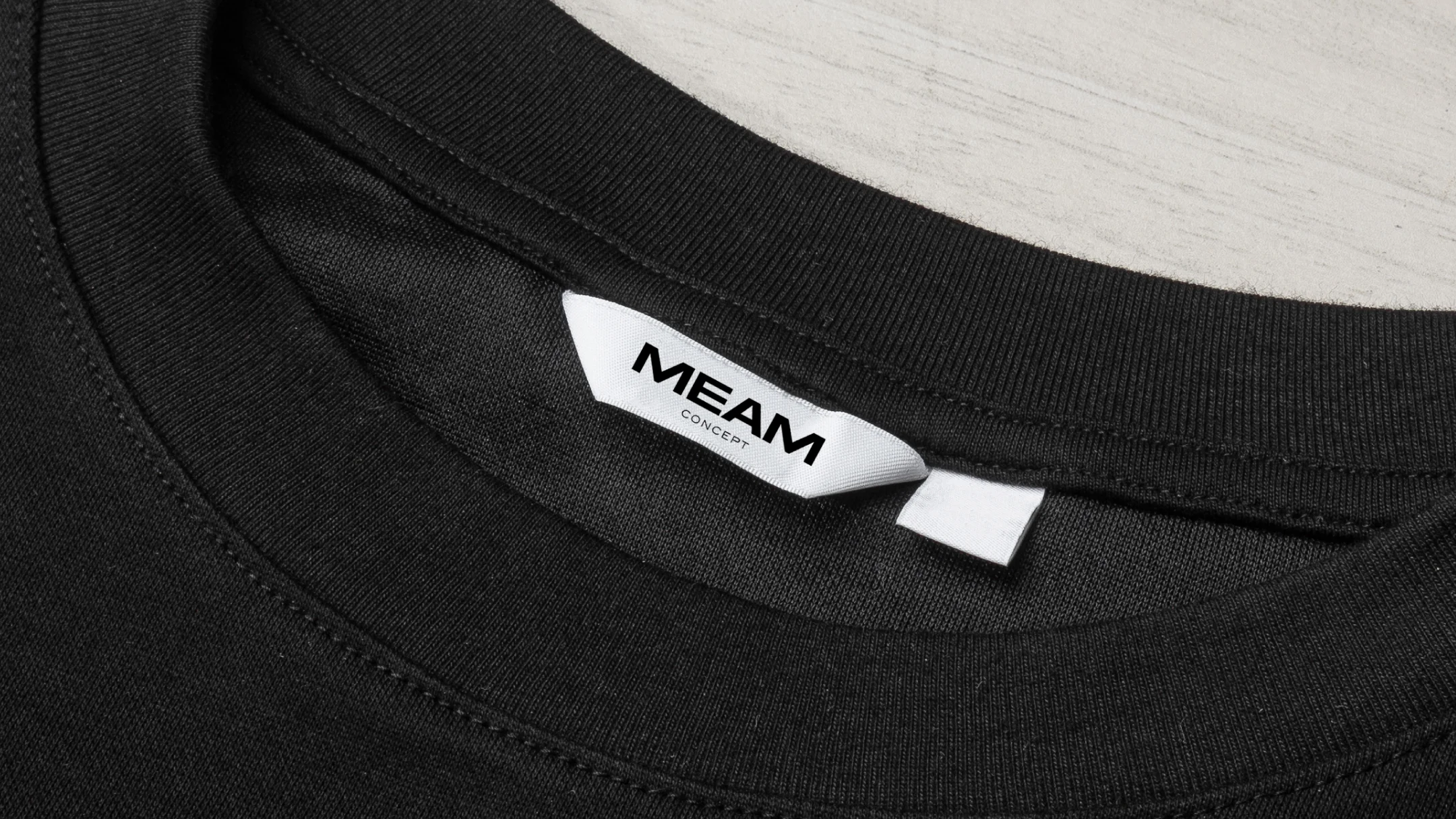 Projeto Meam Concept da Nhdesign: Etiqueta com o logótipo da Meam Concept em t-shirt preta.