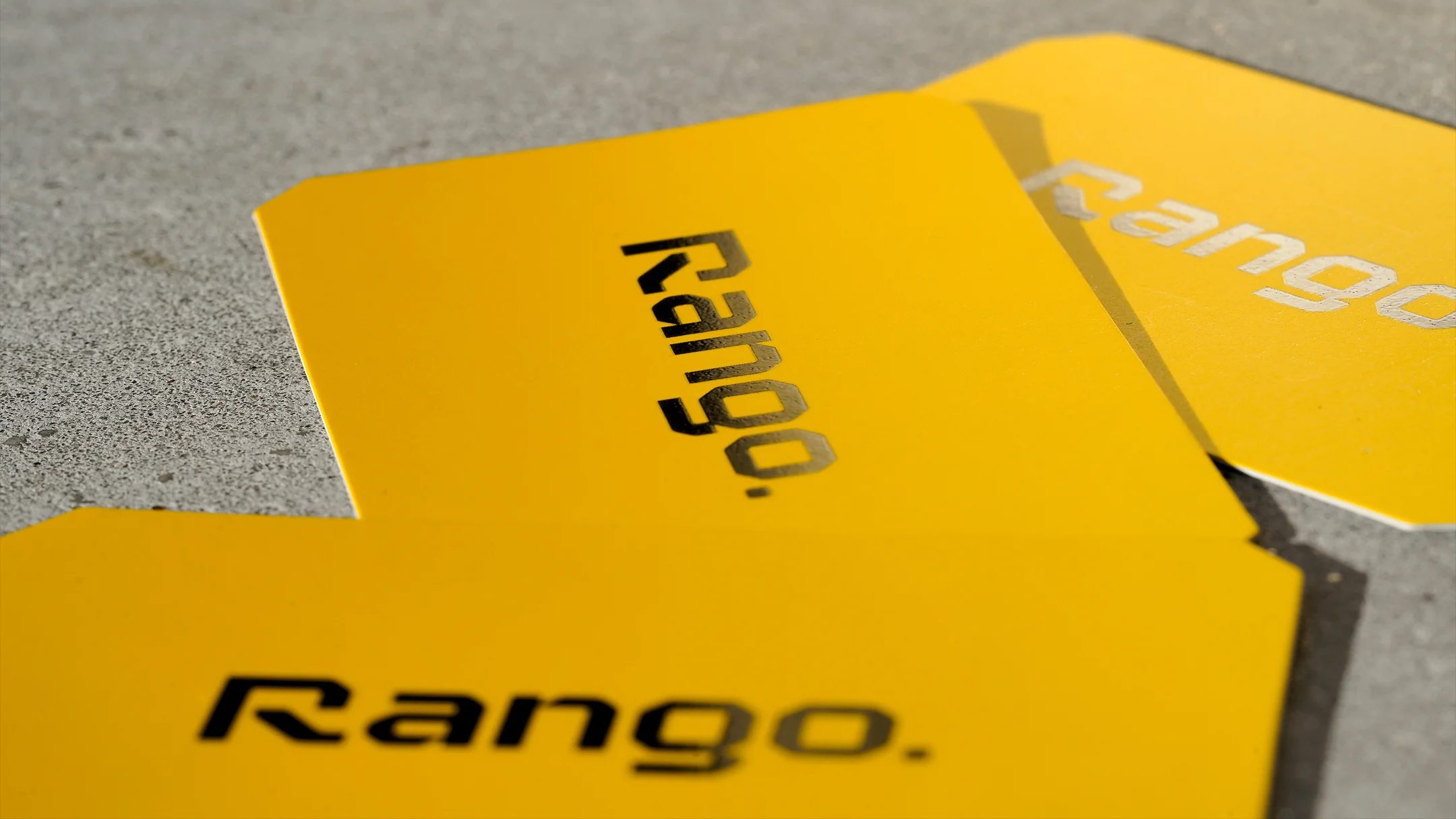 Projeto Rango da Nhdesign: Fotografia do estacionário da Rango sobre chão de cimento: cartões, envelopes e blocos de notas.